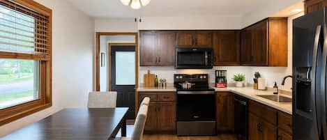 A modern kitchen with wooden cabinets, a black refrigerator, a microwave, and a stove.