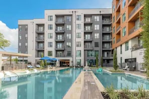 A modern apartment building with a central swimming pool, outdoor seating, and a covered area. - Stylish Austin Domain 1BR | Pool, Gym | King bed (Austin)
