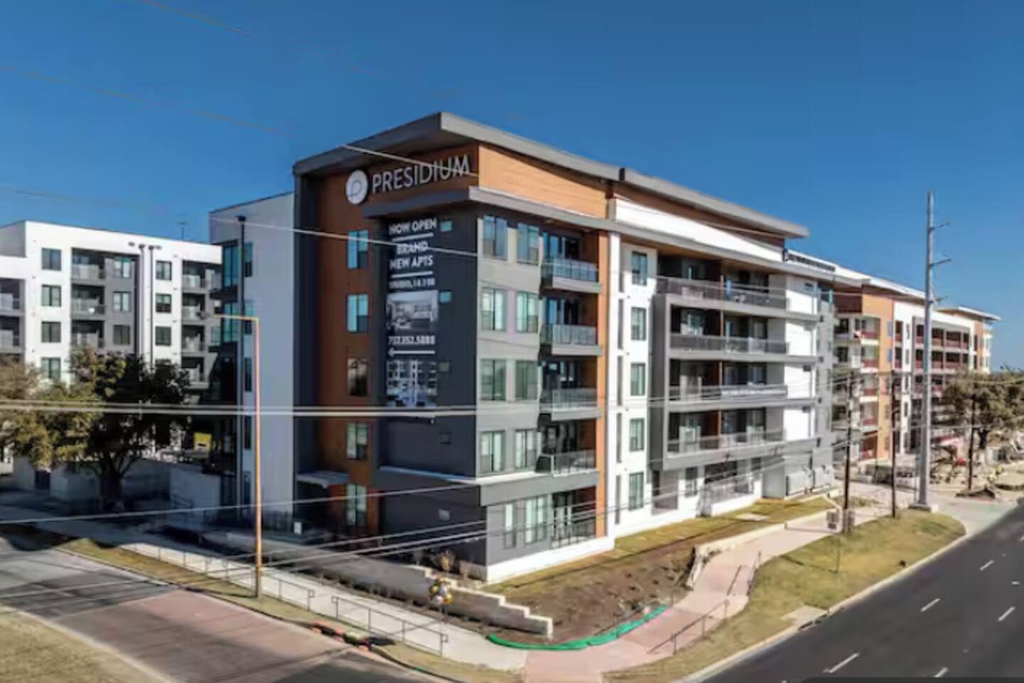 Un immeuble à plusieurs étages, sur lequel on peut lire l’inscription « PRESIDIUM » et « NOUVEAUX APPARTEMENTS, OUVERTURE IMMINENTE ».