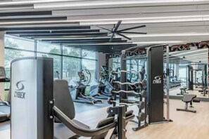 Et fitnessrum med træningsmaskiner, styrkeudstyr og spejle.