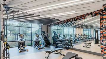 Un gimnasio con diverso equipamiento de ejercicio, amplias ventanas y un diseño moderno.