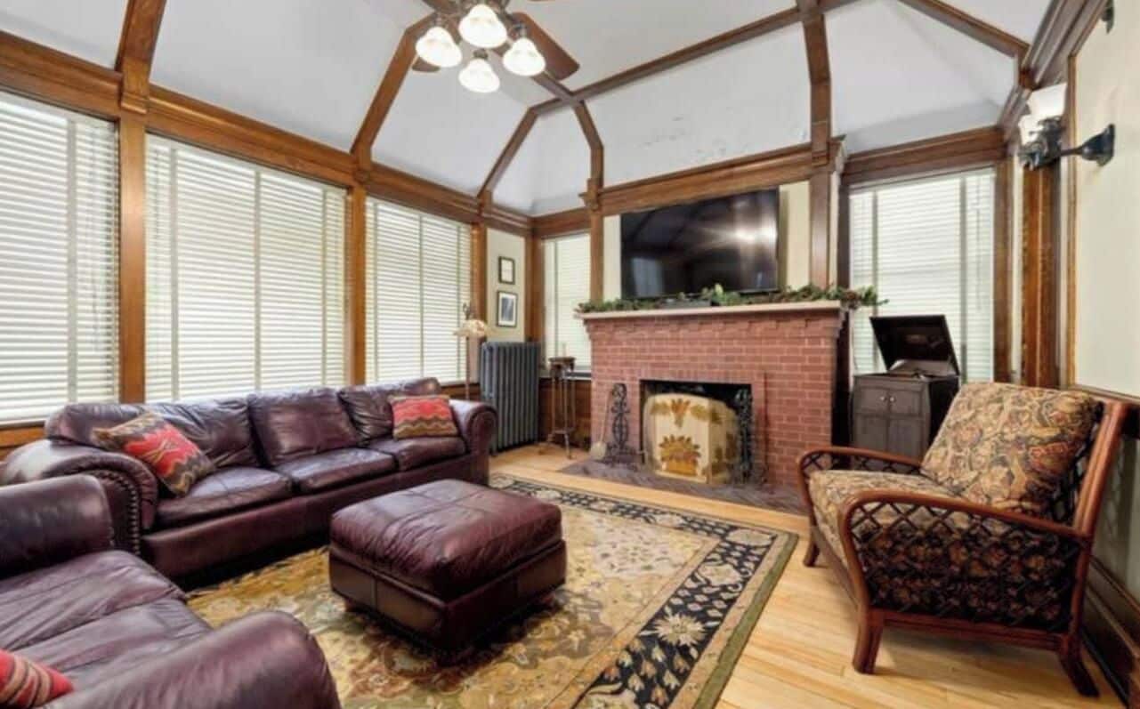 Ein großzügiger Wohnraum mit Kamin, Ledersofas und einem gemusterten Teppich.