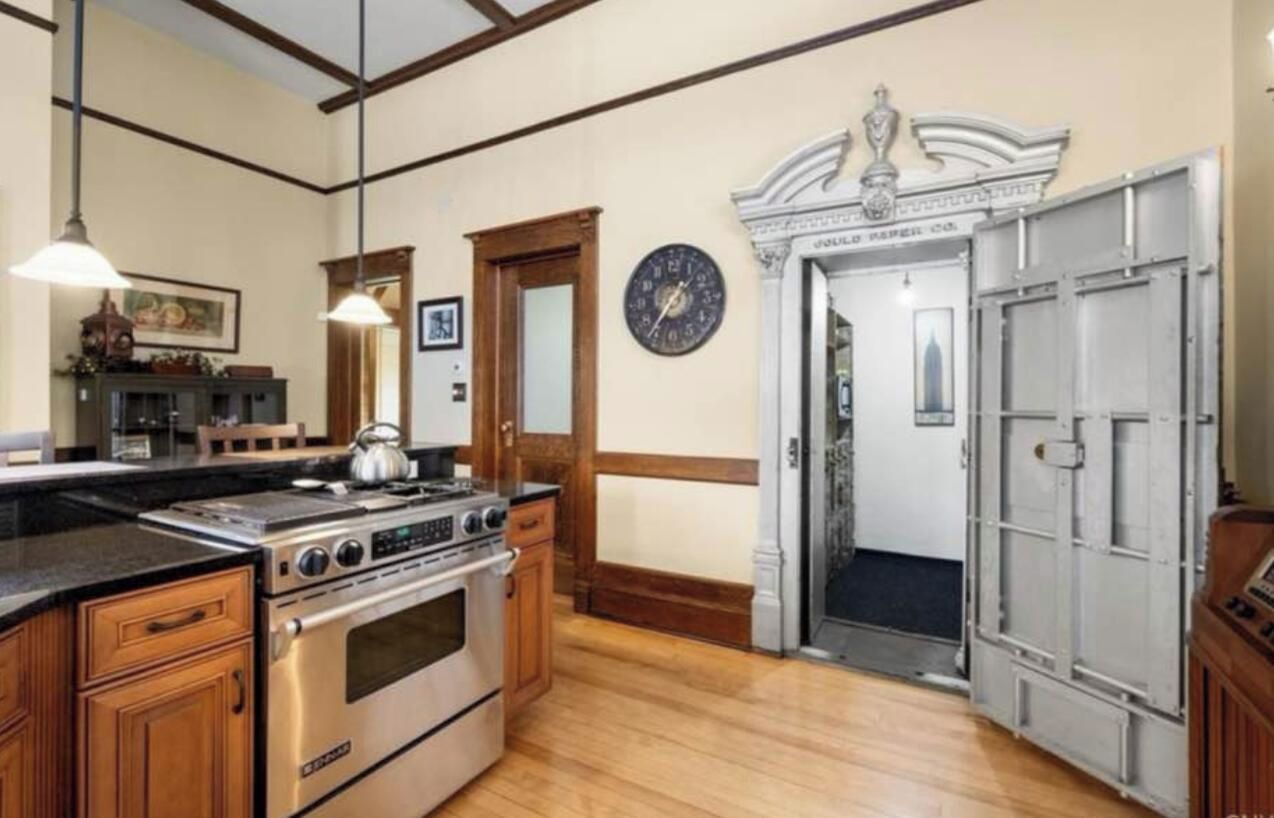 A kitchen with wooden cabinets, a stove, and a clock on the wall.