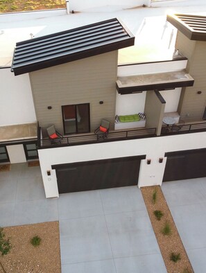 A modern building with a flat roof, a garage, and a patio area with seating. - Private hot tub| EV Charger| Near Zion| Sleeps 8 (Kanab)