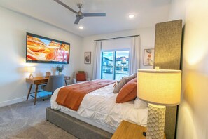 A modern bedroom with a bed, desk, and a large window. - Private hot tub| EV Charger| Near Zion| Sleeps 8 (Kanab)