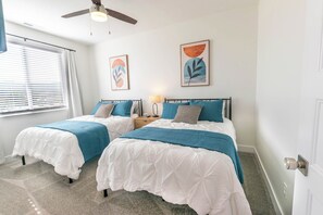 A bedroom with two beds, a ceiling fan, artwork on the walls, and a window with blinds. - Private hot tub| EV Charger| Near Zion| Sleeps 8 (Kanab)