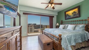 Ein Schlafzimmer mit einem großen Bett, einem Deckenventilator, einem Fernseher und Blick auf die Stadt durch eine Schiebetür.