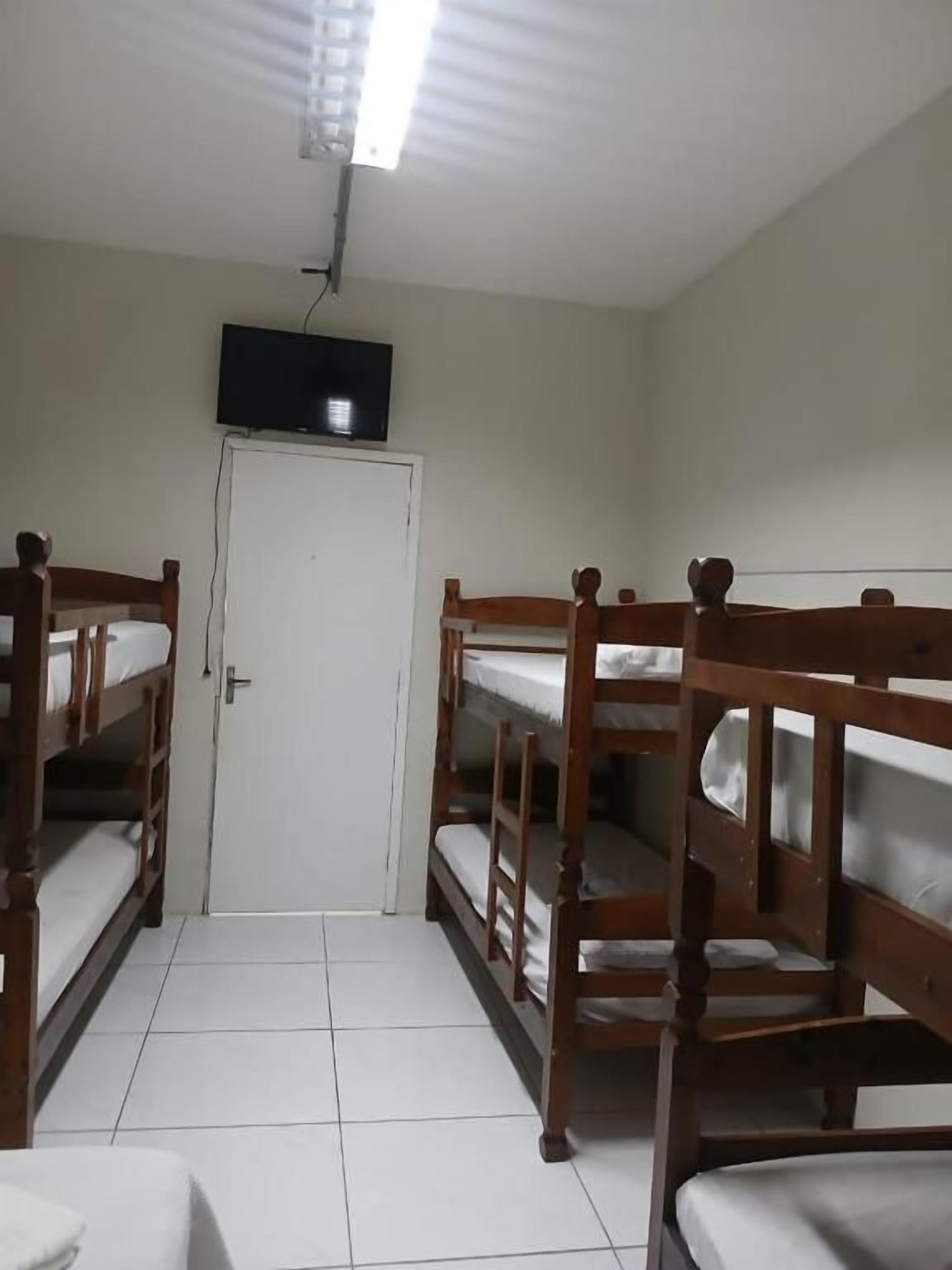 A room with bunk beds, a television, and a door.
