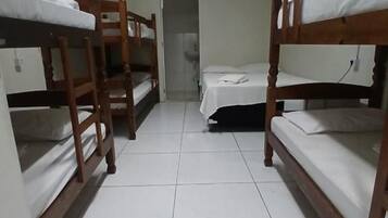 A room with bunk beds, a door, and a ceiling fan.