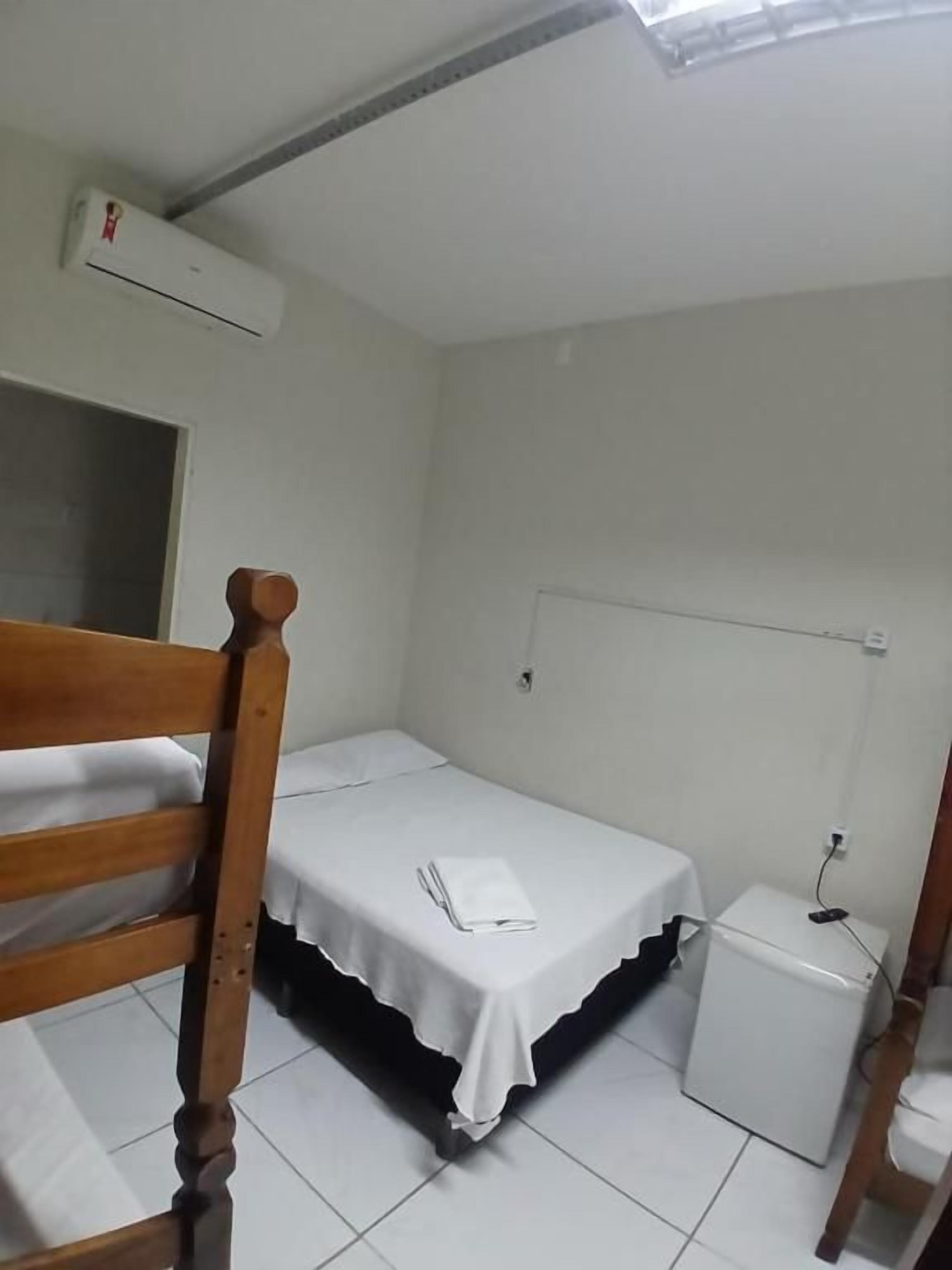 Ein kleines, sauberes Zimmer mit einem Einzelbett, einem Nachttisch und einem Fenster mit Blick.