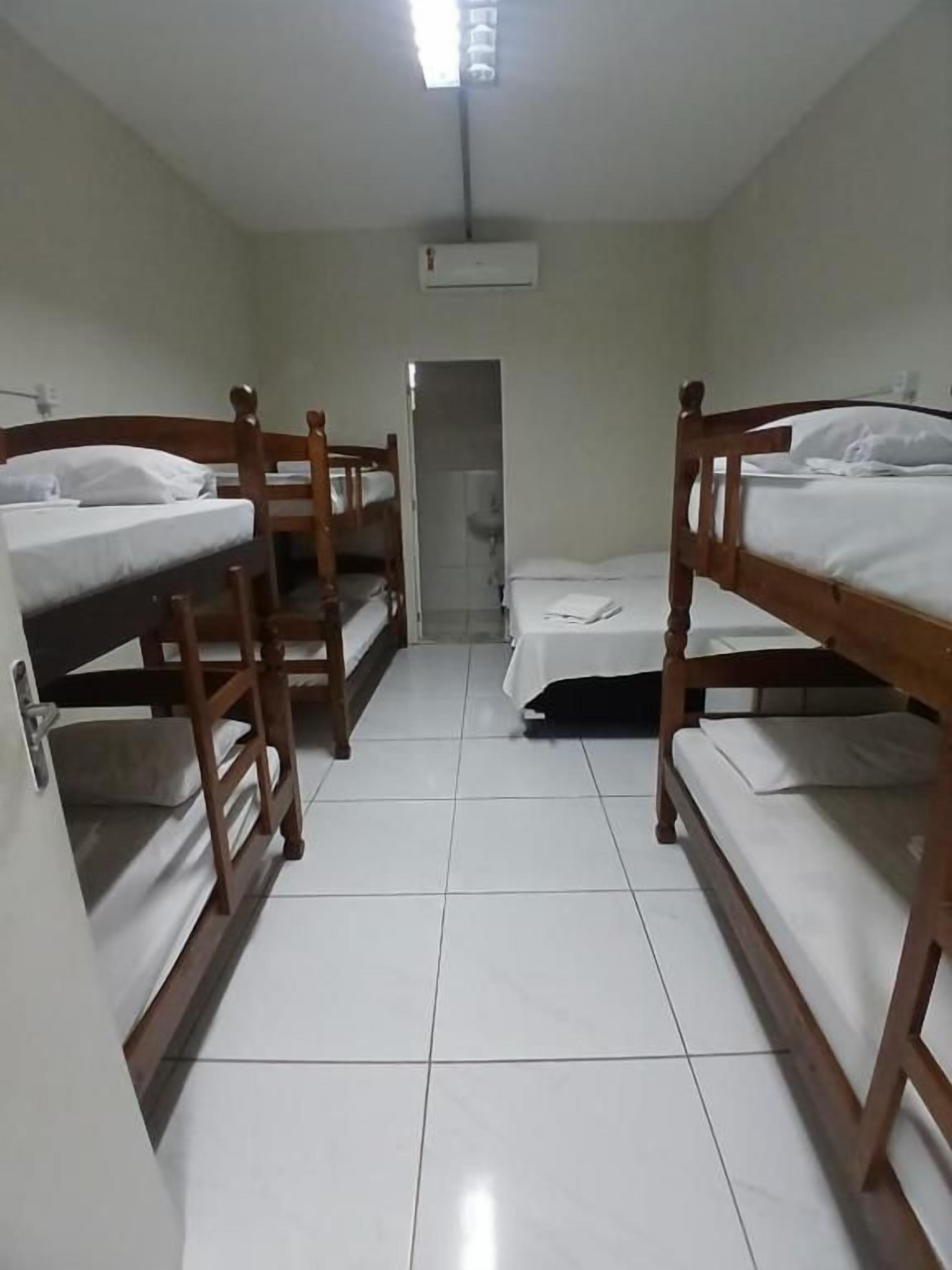A room with four bunk beds, a tiled floor, a door, and an air conditioning unit.