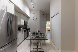 A modern kitchen with stainless steel appliances, a glass dining table, and a clock on the wall. - 2BR Townhouse | Fort York, Steps to the Lake (Toronto)
