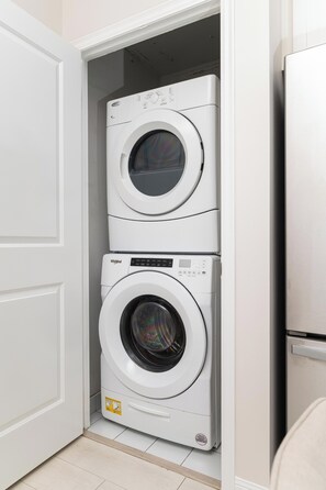 A compact laundry room with two stacked front-loading washing machines. - 2BR Townhouse | Fort York, Steps to the Lake (Toronto)