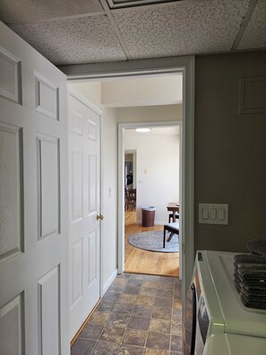 Une pièce avec une porte blanche, un tapis, une table à manger et une chaise.