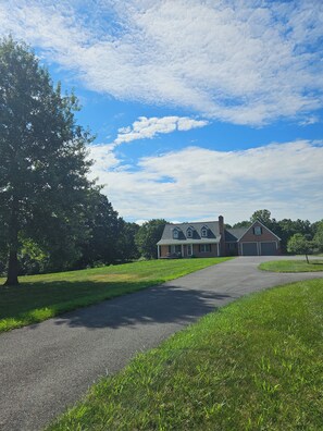 A house with a driveway leading to a garage, surrounded by grass and trees. - Peaceful Country 3 Bedroom Home near Martinsburg, Shepherdstown and Hagerstown. (Martinsburg)