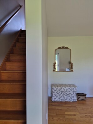 A wooden staircase leading to a room with a large mirror, a bench, and a basket on the floor. - Peaceful Country 3 Bedroom Home near Martinsburg, Shepherdstown and Hagerstown. (Martinsburg)