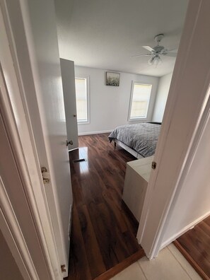 Een slaapkamer met een bed, een plafondventilator en een raam.