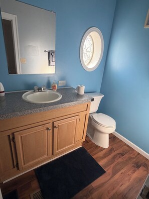 Een badkamer met een wastafel, spiegel, toilet en een raam met decoratief glaswerk.