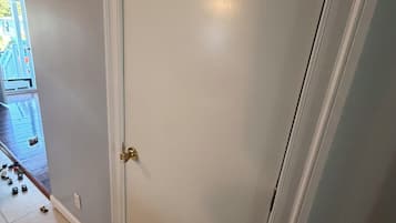 Una puerta cerrada con manija de latón, piso de baldosas y un enchufe visible.