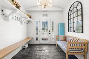 Un interior acogedor con un banco, un sofá, un muro decorativo y una puerta con paneles de vidrio esmerilado.
