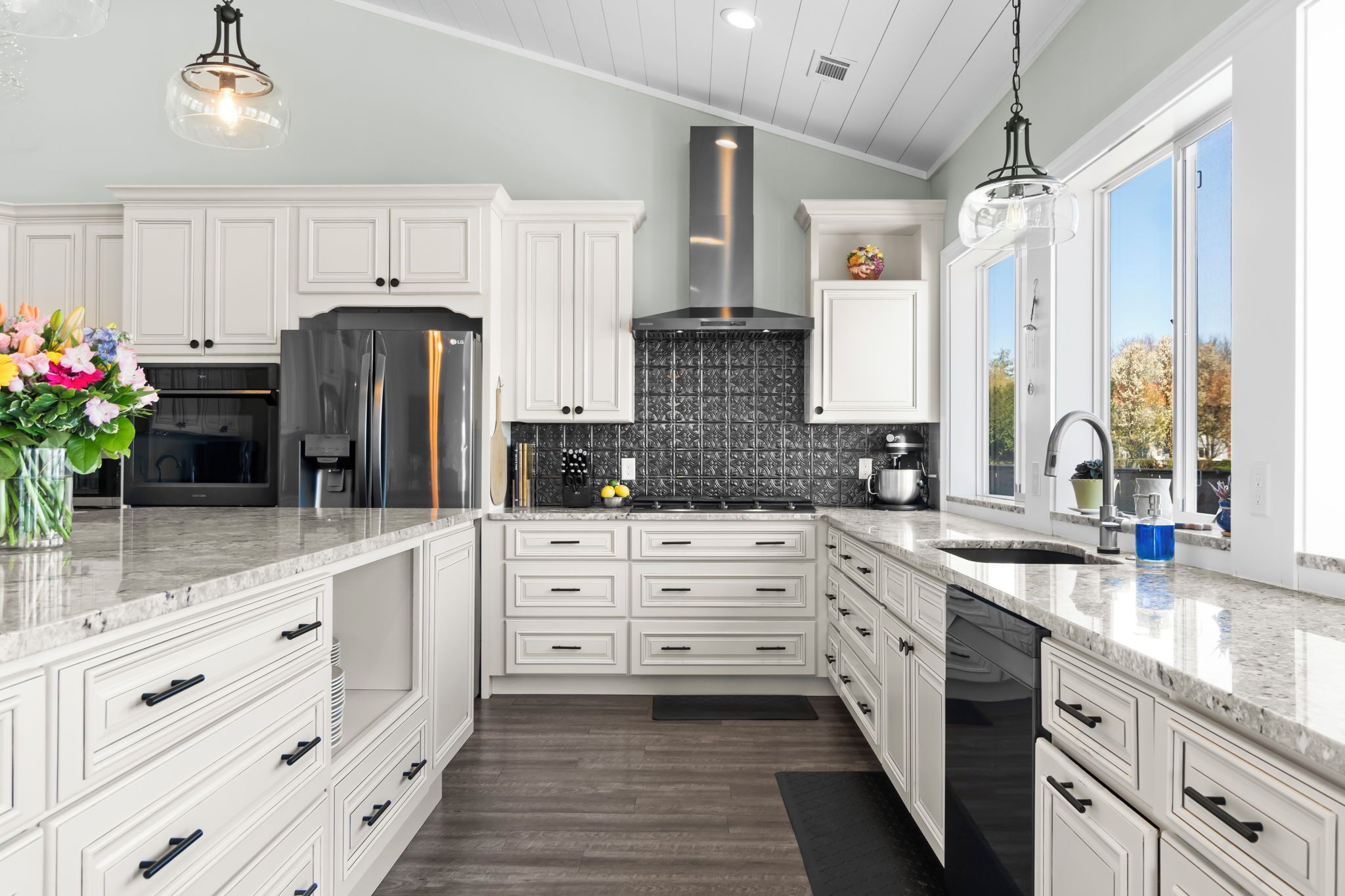 Una cocina moderna con armarios blancos, un refrigerador de acero inoxidable y un ventanal que proporciona luz natural.