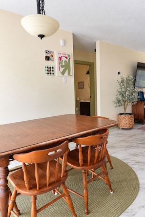 Ein Essbereich mit einem Holztisch und Stühlen, einer Hängeleuchte und einer Wand mit gerahmten Bildern.
