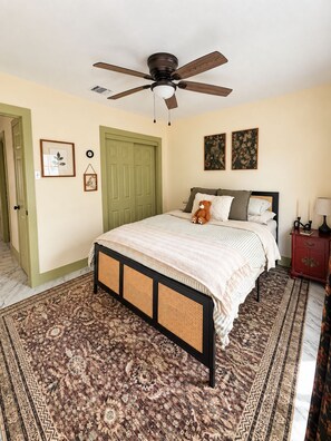 Une chambre à coucher avec un lit, un ventilateur de plafond, une porte et un tapis.