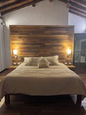 A bed with a wooden headboard, two bedside lamps, and a bedside table.