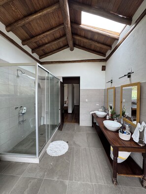 A modern bathroom with a glass-enclosed shower, wooden beams on the ceiling, and a vanity with two sinks. - Fantastic 4-bedroom house in Cusco perfect for your getaway (Cusco)