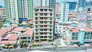 Un edificio de varios pisos con balcones, un estacionamiento y una calle con vehículos.