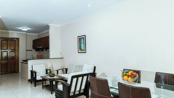 A modern living room with a dining area, a kitchen in the background, and a framed artwork on the wall.