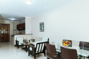 Uma sala de estar moderna com área de jantar, cozinha ao fundo e uma obra de arte emoldurada na parede.