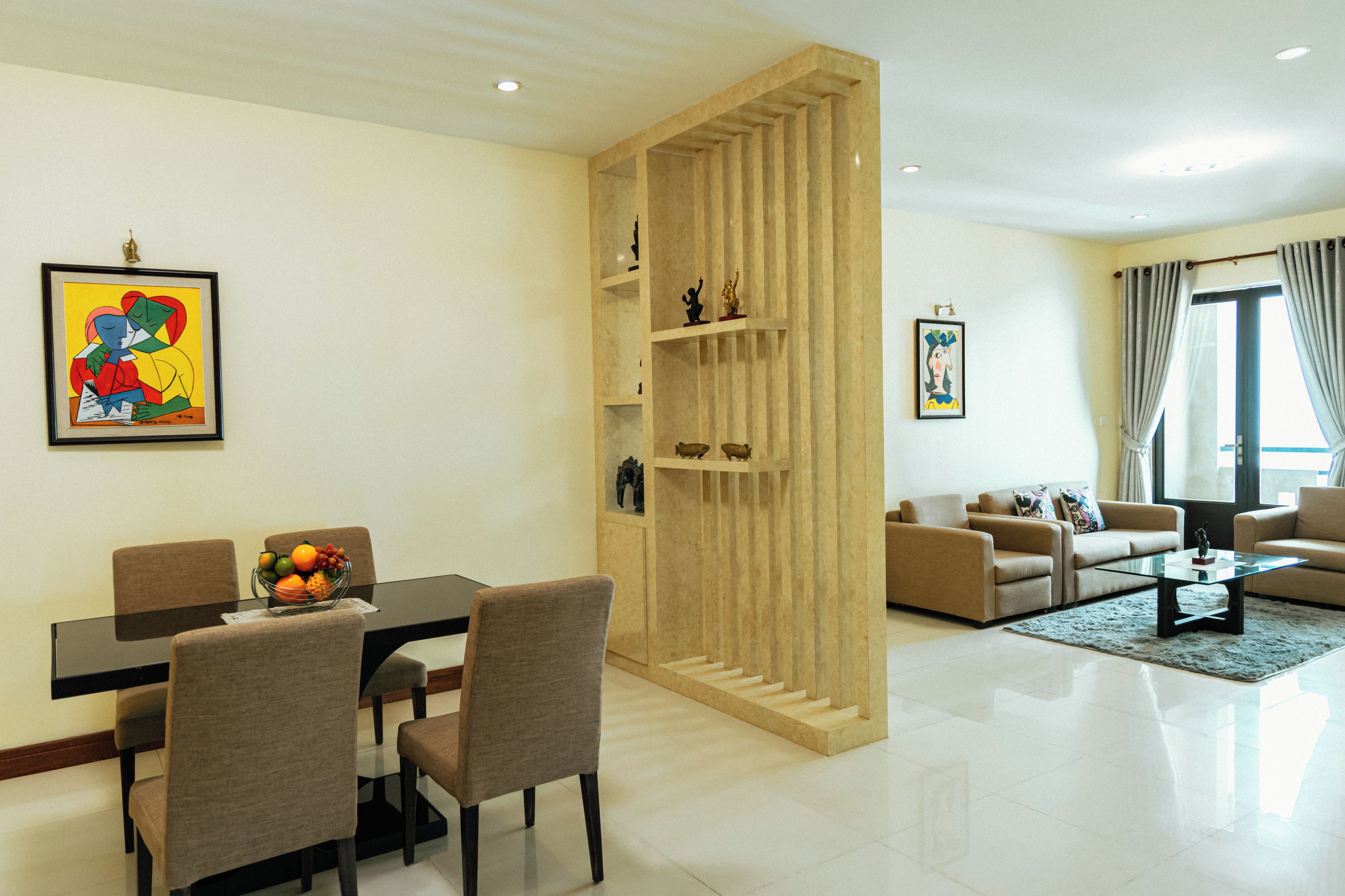 Ein modernes Wohnzimmer mit Essbereich, ausgestattet mit einem Glastisch, Sofas und einer dekorativen Holzvertäfelung.
