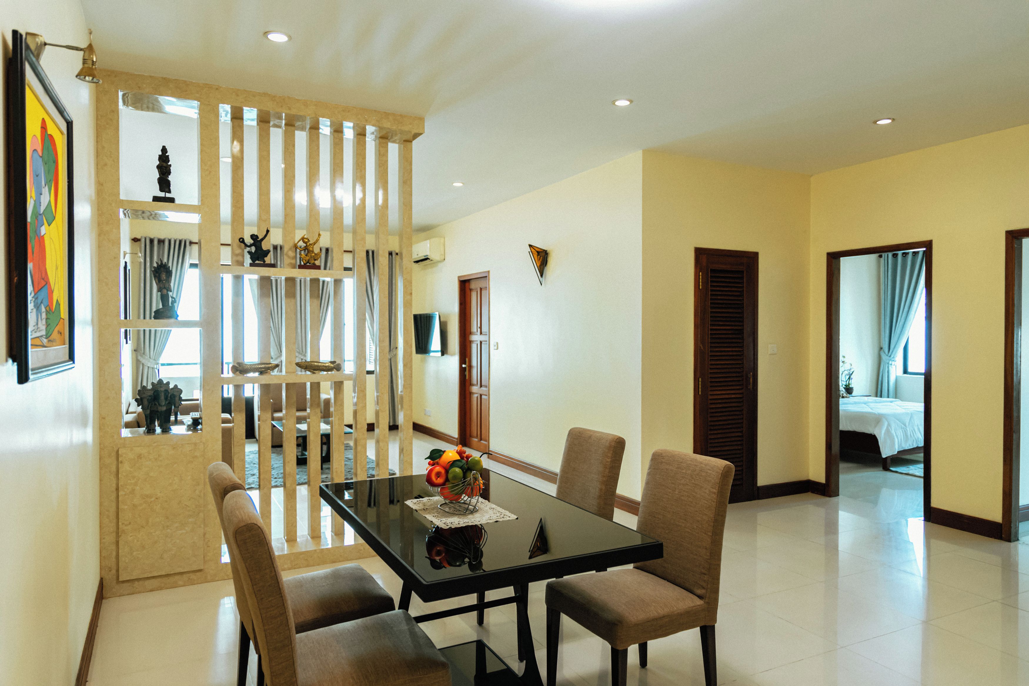 A dining area with a glass table, four chairs, and a decorative centerpiece.