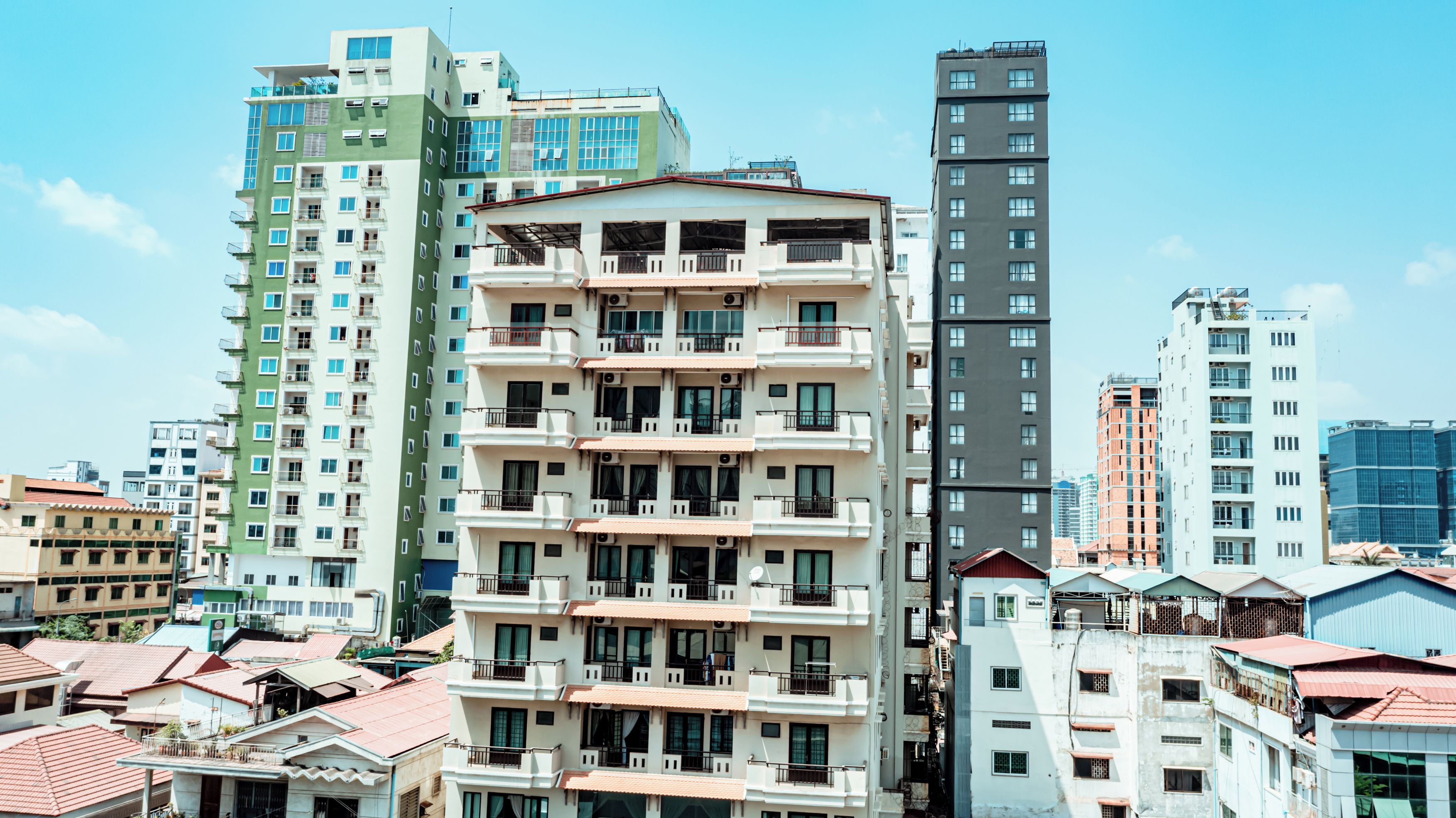 A multi-story residential building with balconies, a flat roof, and a clear sky.