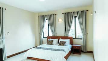 Een slaapkamer met een houten bed, een nachtkastje en een groot raam met gordijnen.