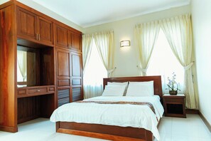 A bedroom with a wooden bed, a nightstand, a dresser, and a mirror. - Residence 43 (Makara, Phnom Penh)