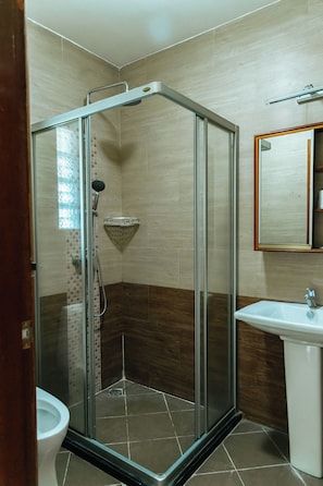 Box de chuveiro com porta de vidro, chuveiro e mangueira.
