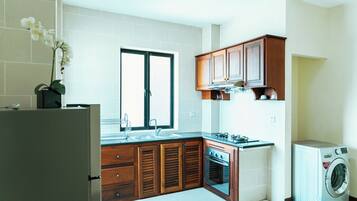 A modern kitchen with wooden cabinets, a built-in oven, a sink, and a washing machine.