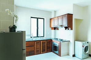 Una cocina moderna con armarios de madera, horno empotrado, lavaplatos y lavadora.