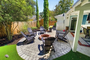 Eine Terrasse mit Adirondack-Stühlen, einer Feuerstelle und einem Holzzaun.