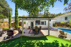Un jardin avec un patio couvert, une piscine et une pelouse.
