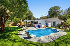 Un jardin avec une piscine, un patio couvert et une petite maison.