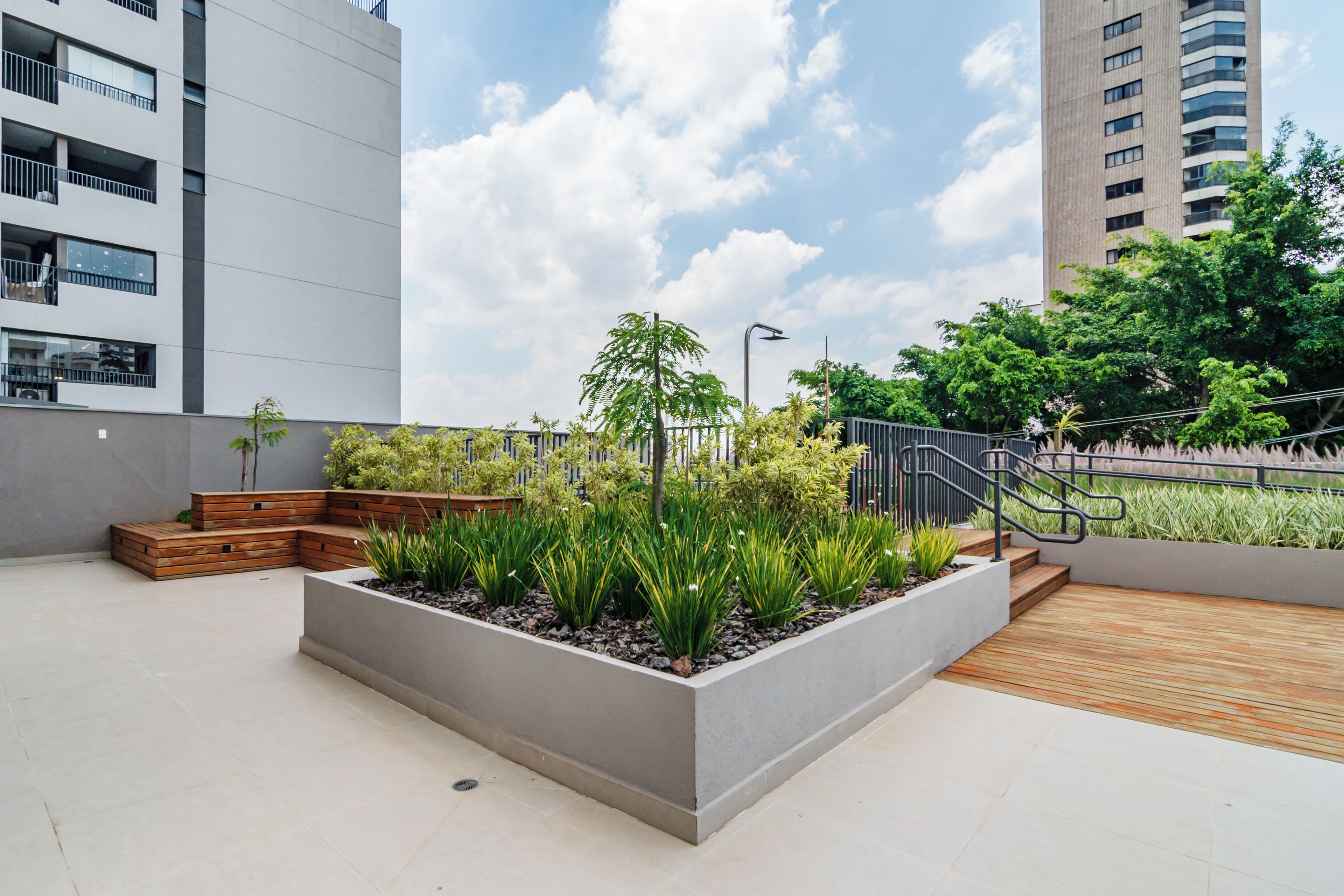 A rooftop garden with planters, wooden steps, and a metal railing.