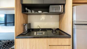 A modern kitchen with a built-in microwave, coffee maker, and a stainless steel sink.