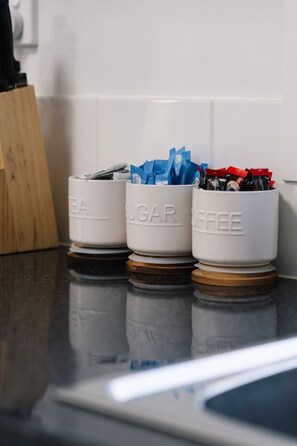Trois récipients blancs, chacun portant une étiquette, sont posés sur un plan de travail de cuisine.