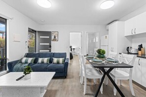 En moderne lejlighed med spiseplads, opholdstue med sofa og køkken.