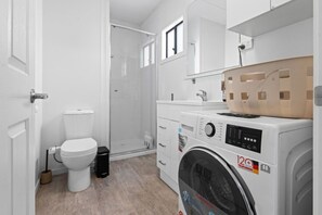 Et moderne badeværelse med toilet, bruser og vaskemaskine.