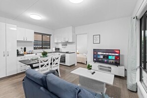 Eine moderne Wohnung mit Küche, Essbereich, Wohnzimmer und Fernseher.