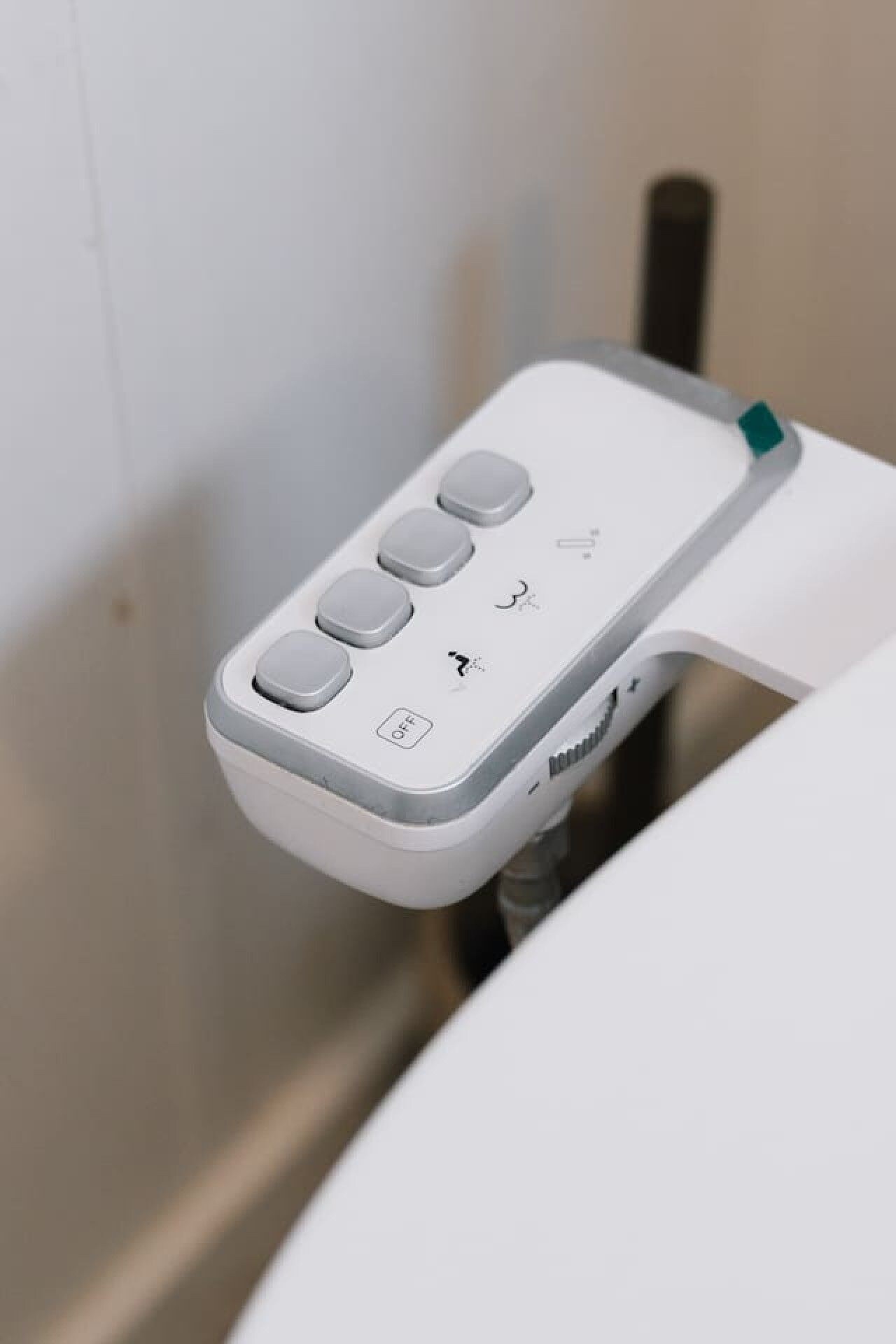 A white toilet with a control panel featuring buttons and a foot pedal.